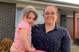 Alicia Forsyth and holds her daughter Harper outside their suburban house.