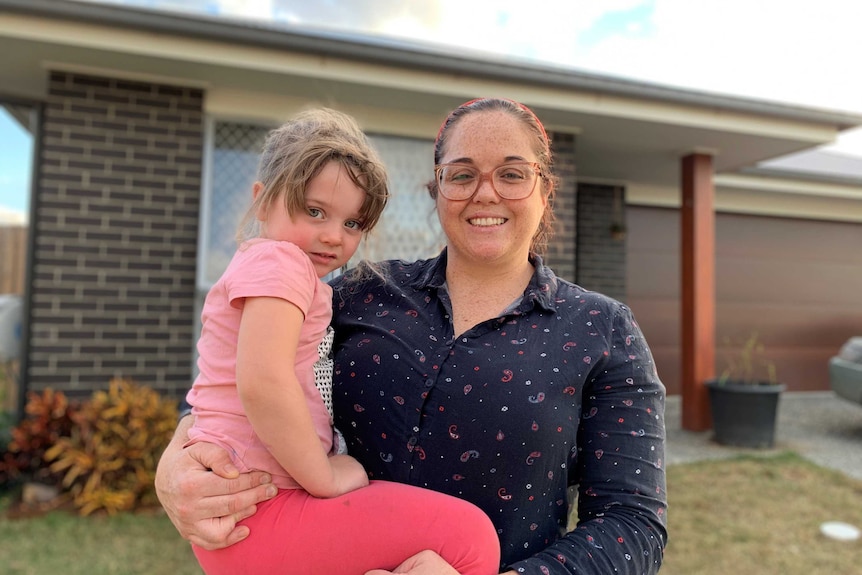 Alicia Forsyth and holds her daughter Harper outside their suburban house.