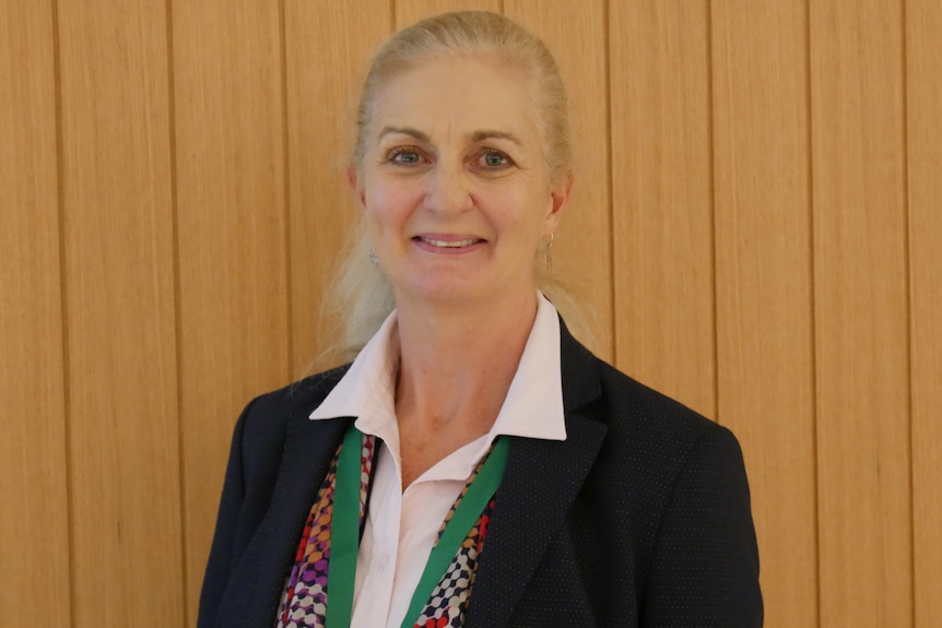 Lady with blonde/grey hair smiles at the camera. 