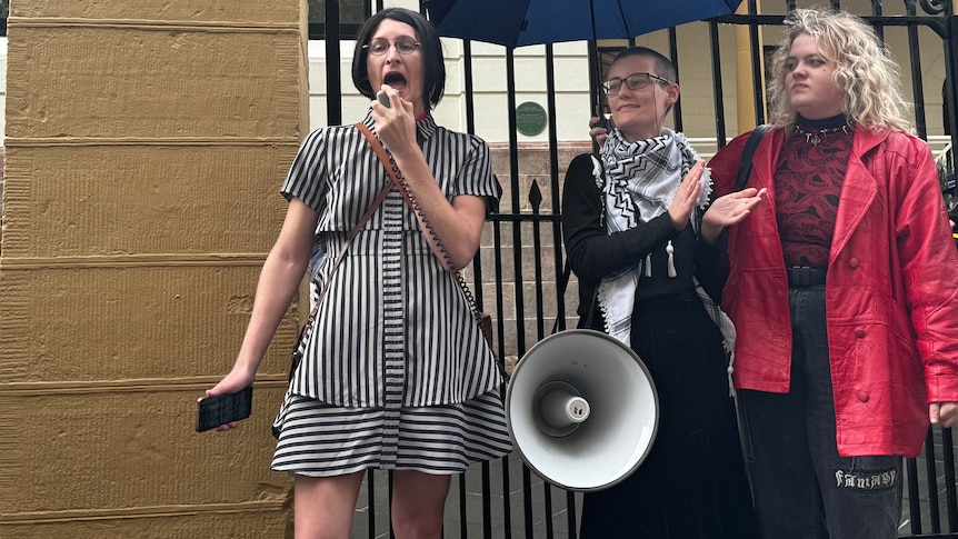 Three women protesting outside NSW parliament house in support of trans rights