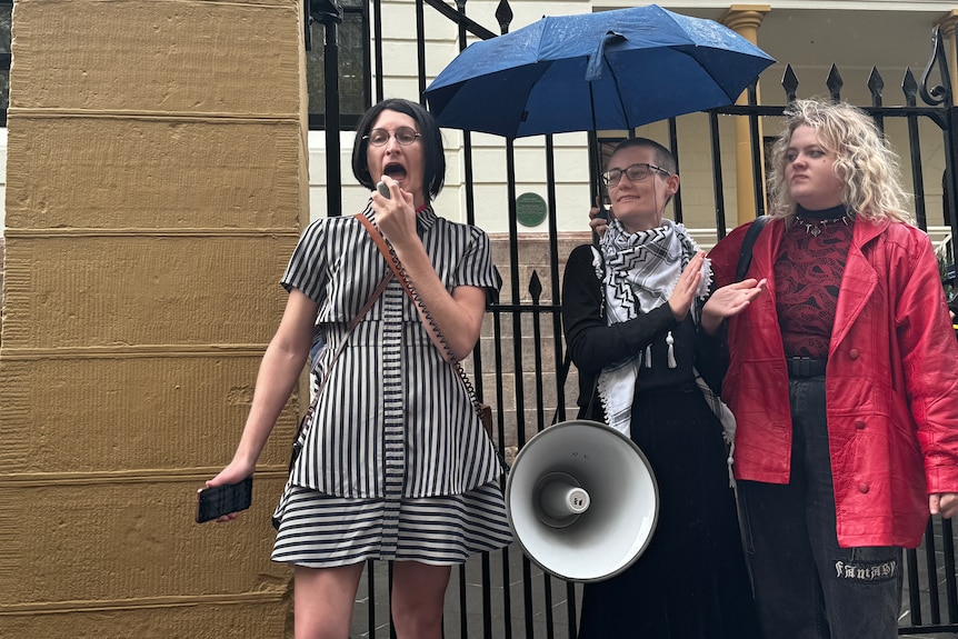 Three women protesting outside NSW parliament house in support of trans rights