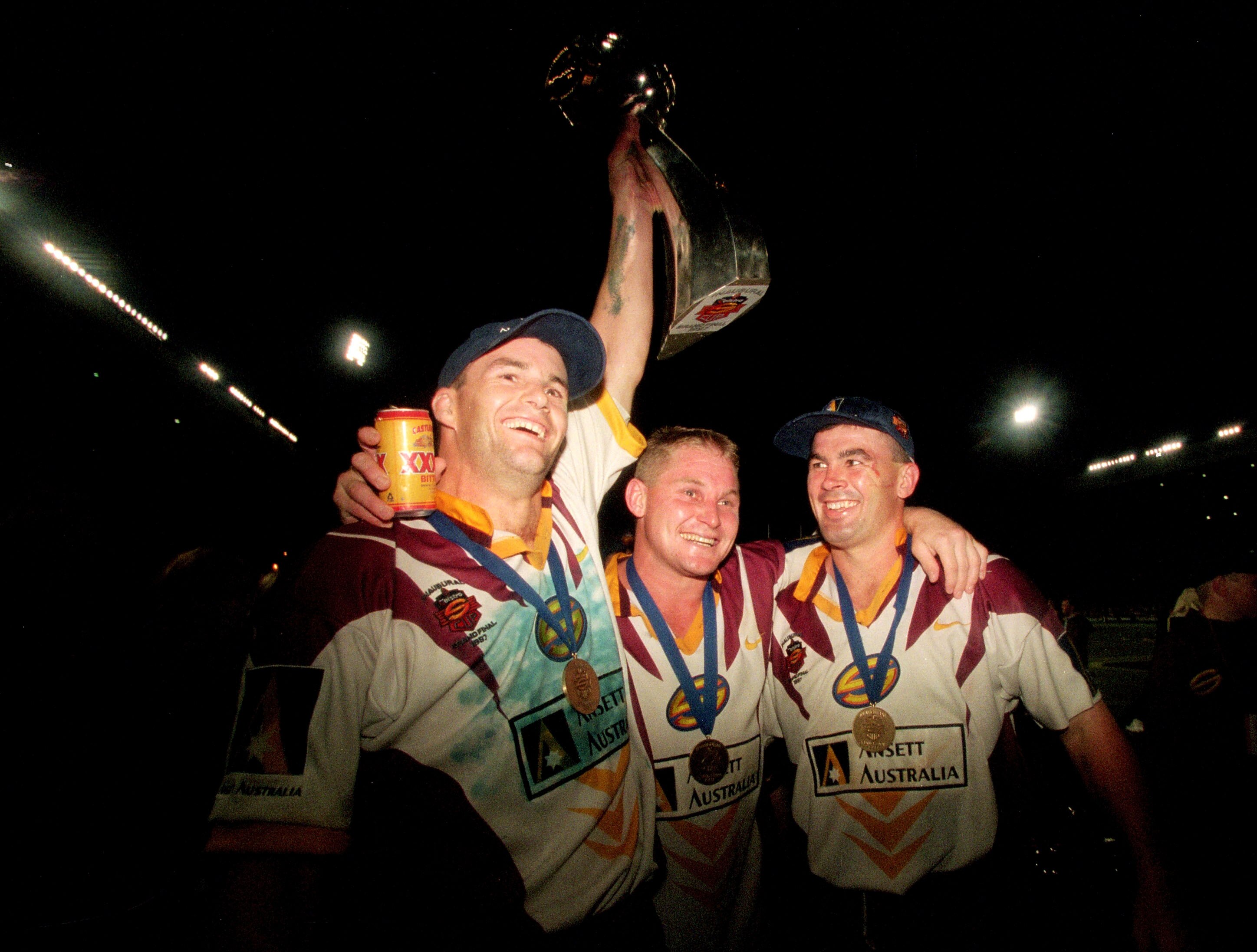 Peter Ryan holds up the Super League trophy as he stands with Brisbane Broncos teammates John Plath and Andrew Gee.