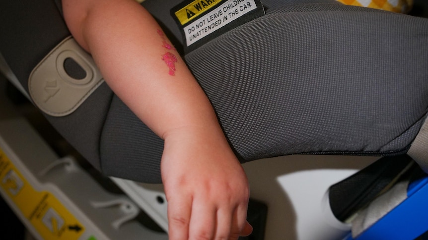Child's arm dangles while in a car seat. 