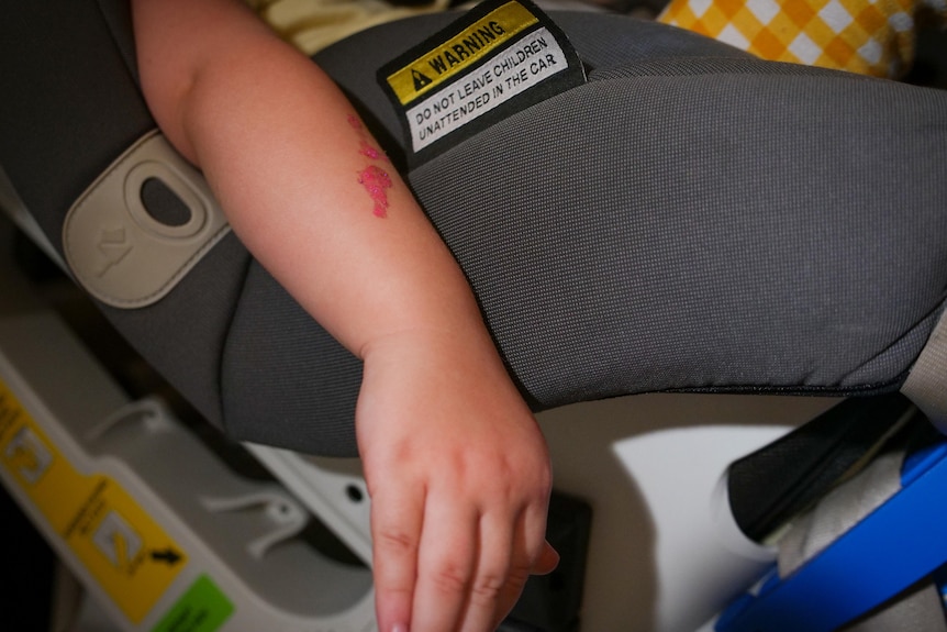 Child's arm dangles while in a car seat. 