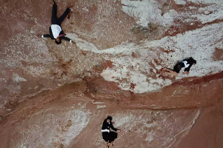 An aerial shot of Kwongkan teams members sprawled out on red rock.
