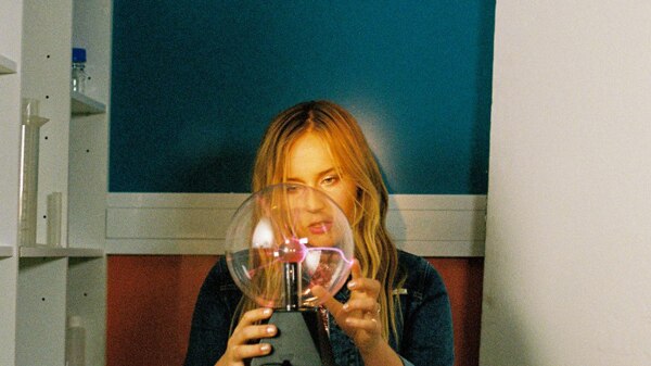 An image of the artist Jack River with her hands around a glowing magnetic orb