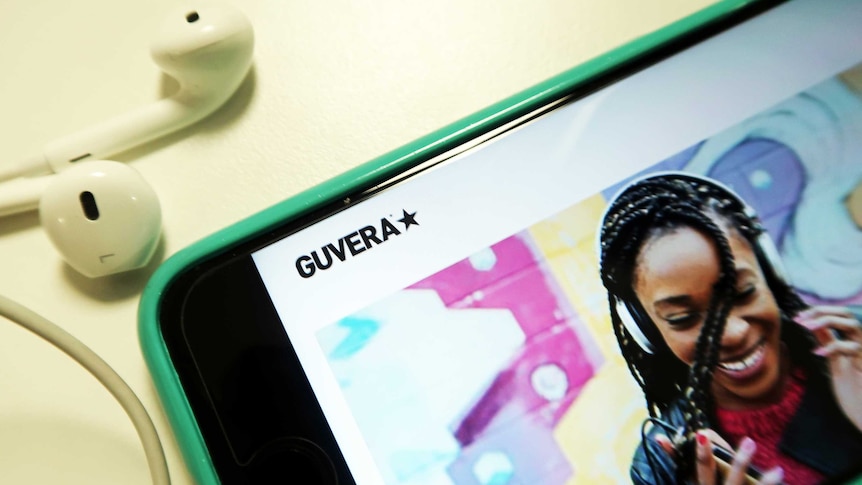 Mobile phone showing Guvera music sharing app and earphones