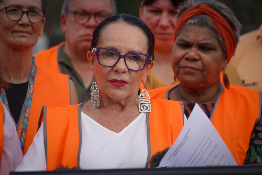 Indigenous Affairs Minister Linda Burney in a high vis vest, standing in front of a group of people and addressing the media.