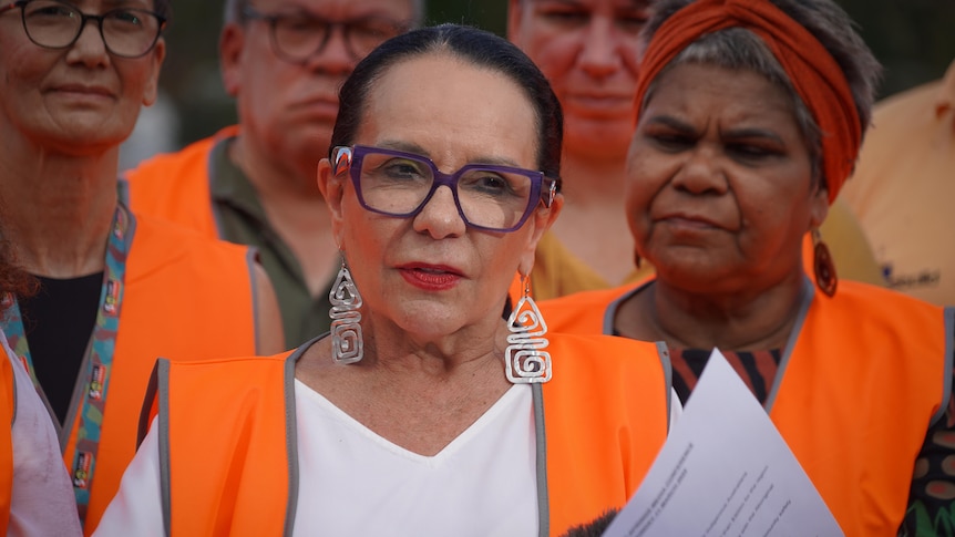 Indigenous Affairs Minister Linda Burney in a high vis vest, standing in front of a group of people and addressing the media.