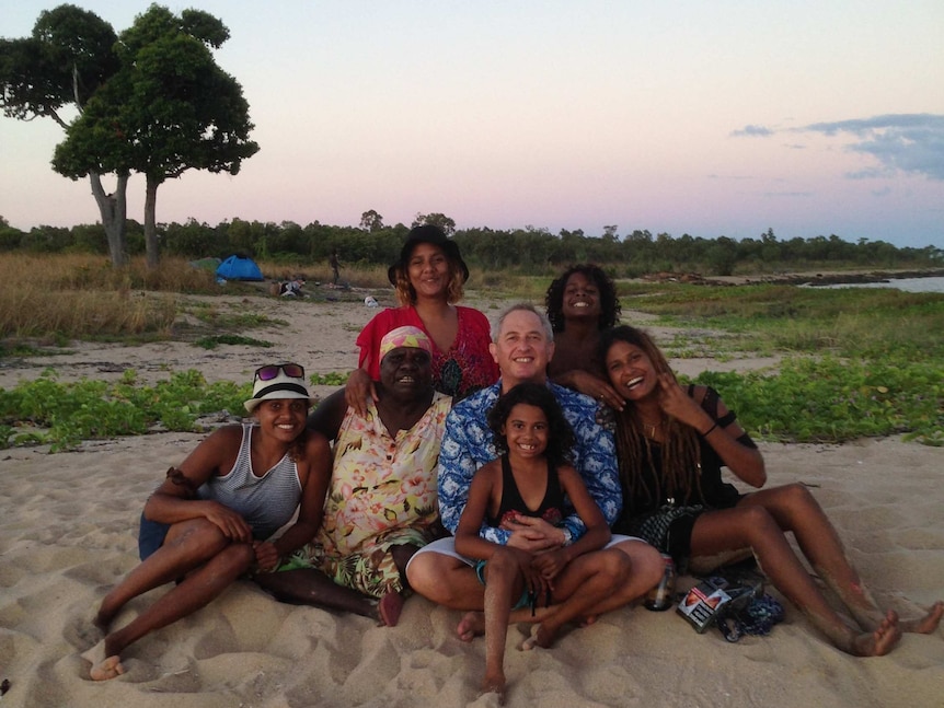 Alice Eather and her family sit on a beach during a sunset
