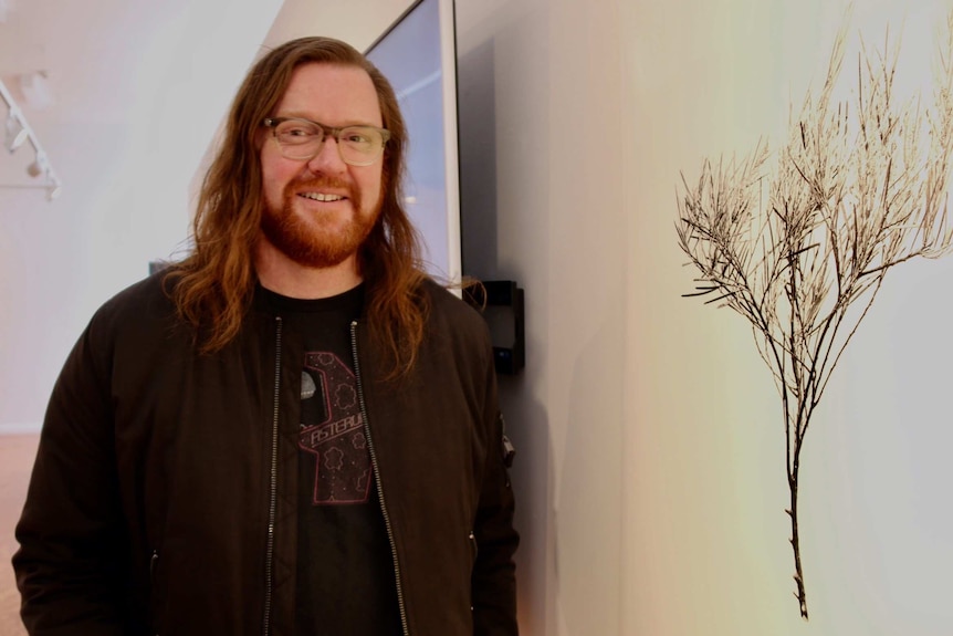 A portrait of Canberra photographer Mark Mohell standing in an art gallery.