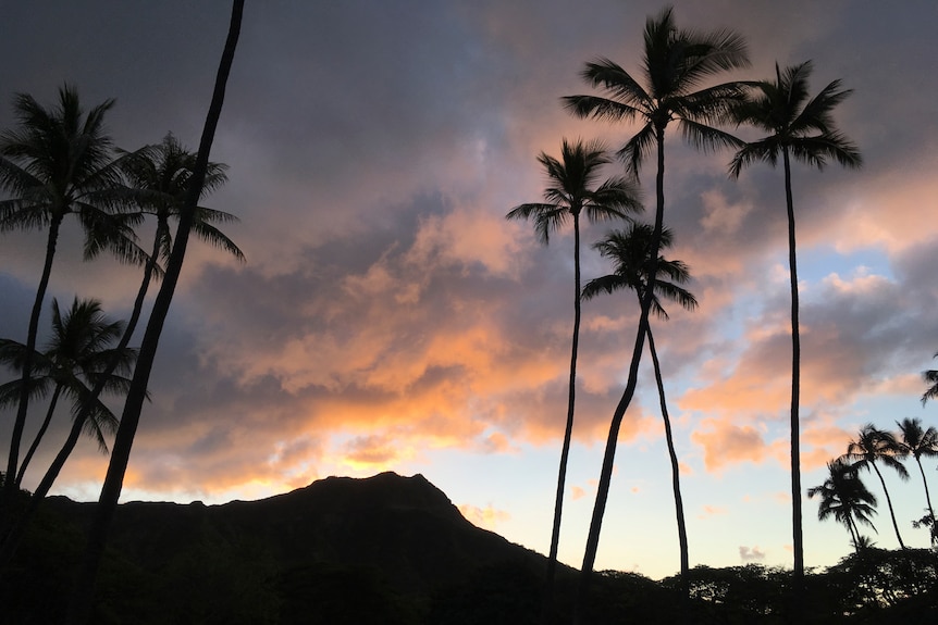 The sun rises behind the Diamond Head State Monument in Honolulu