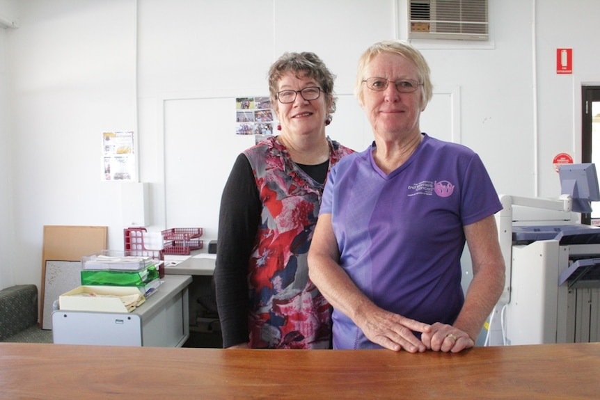 Two women standing behind a desk in an office.