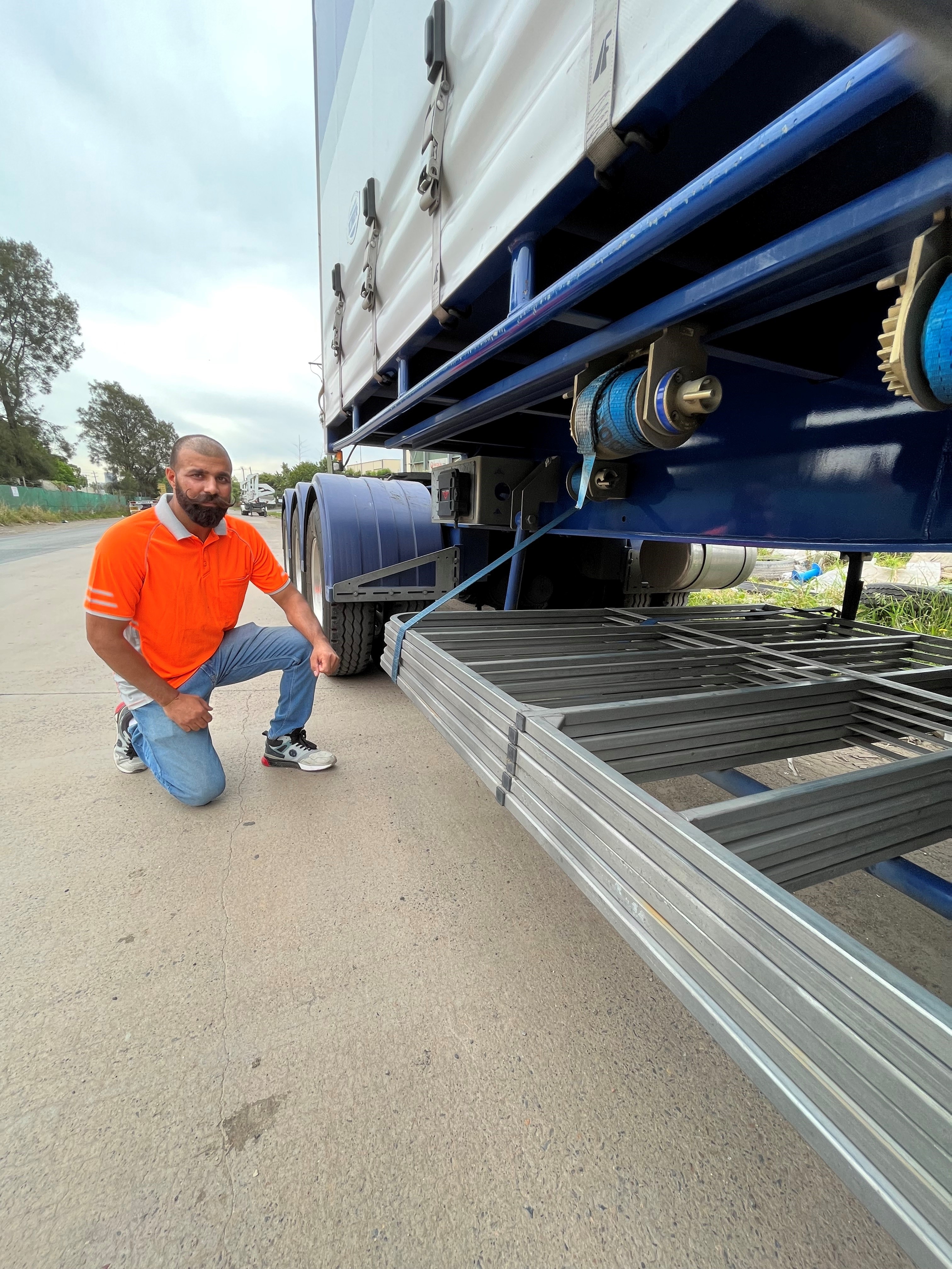 A man kneels down in front of a truck trailer.