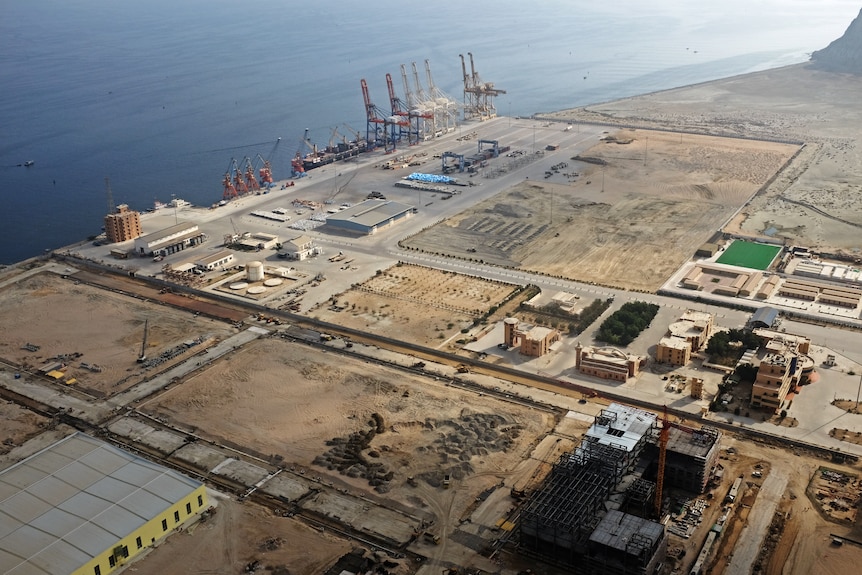 An aerial view of dirt land with roads lined and machines on the edge overlooking water