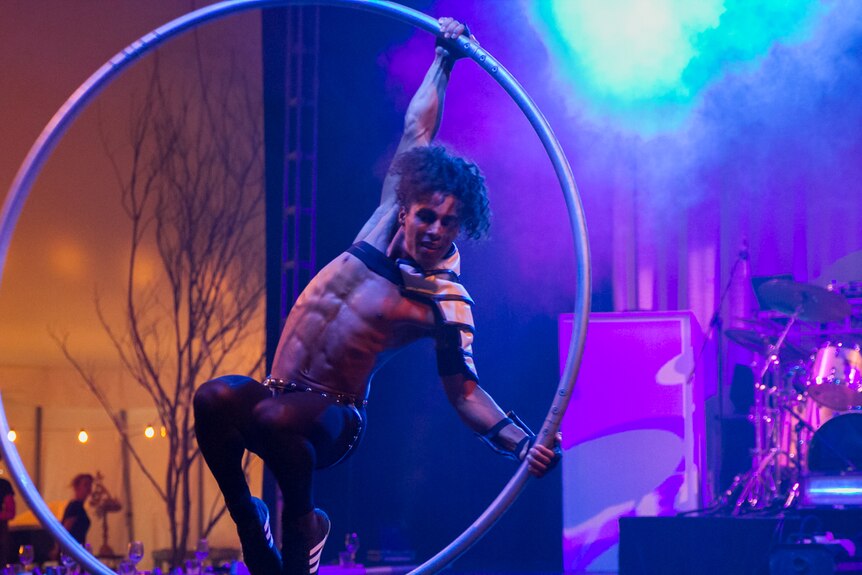 Fear and Delight performer takes a side swing within the hoop on stage.