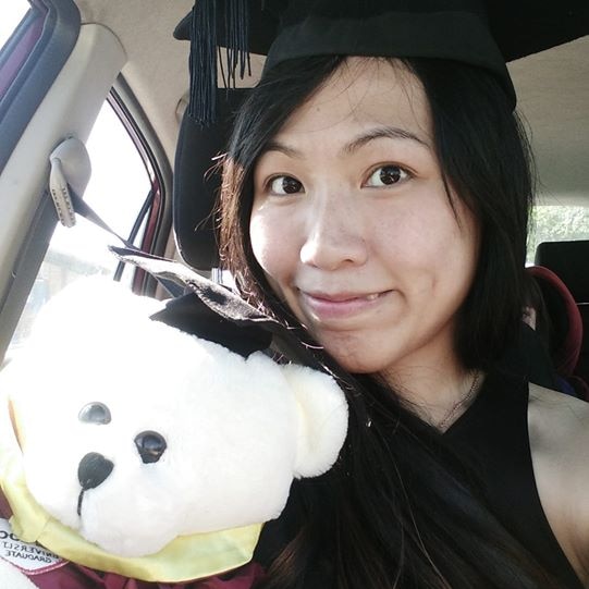 Evelin Kwok is wearing a graduation cap and holding a bear. She is smiling.