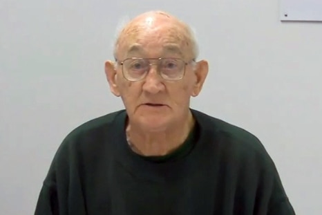 Un anciano con gafas, el pedófilo Gerald Ridsdale, se sienta frente a una pared en blanco.
