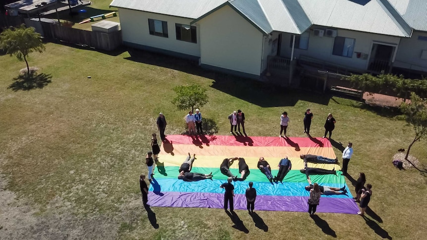 Giant rainbow flag on floor of country hall.