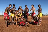 A group of 10 Indigenous men and boys pose painted up for a dance.