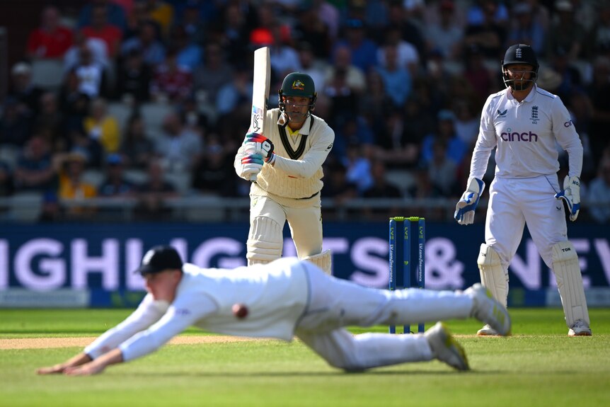 An England fielder dives but misses the ball as Alex Carey watches on