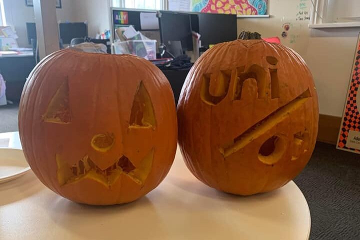 Pumpkins carved with a sad face and the words uni and on 