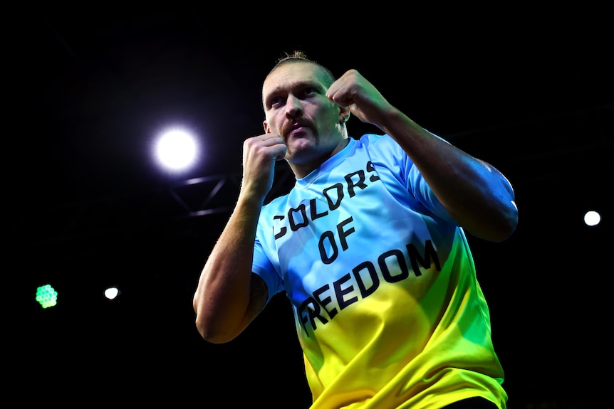 Oleksandr Usyk poses wearing a blue and yellow shirt with COLORS OF FREEDOM written on it