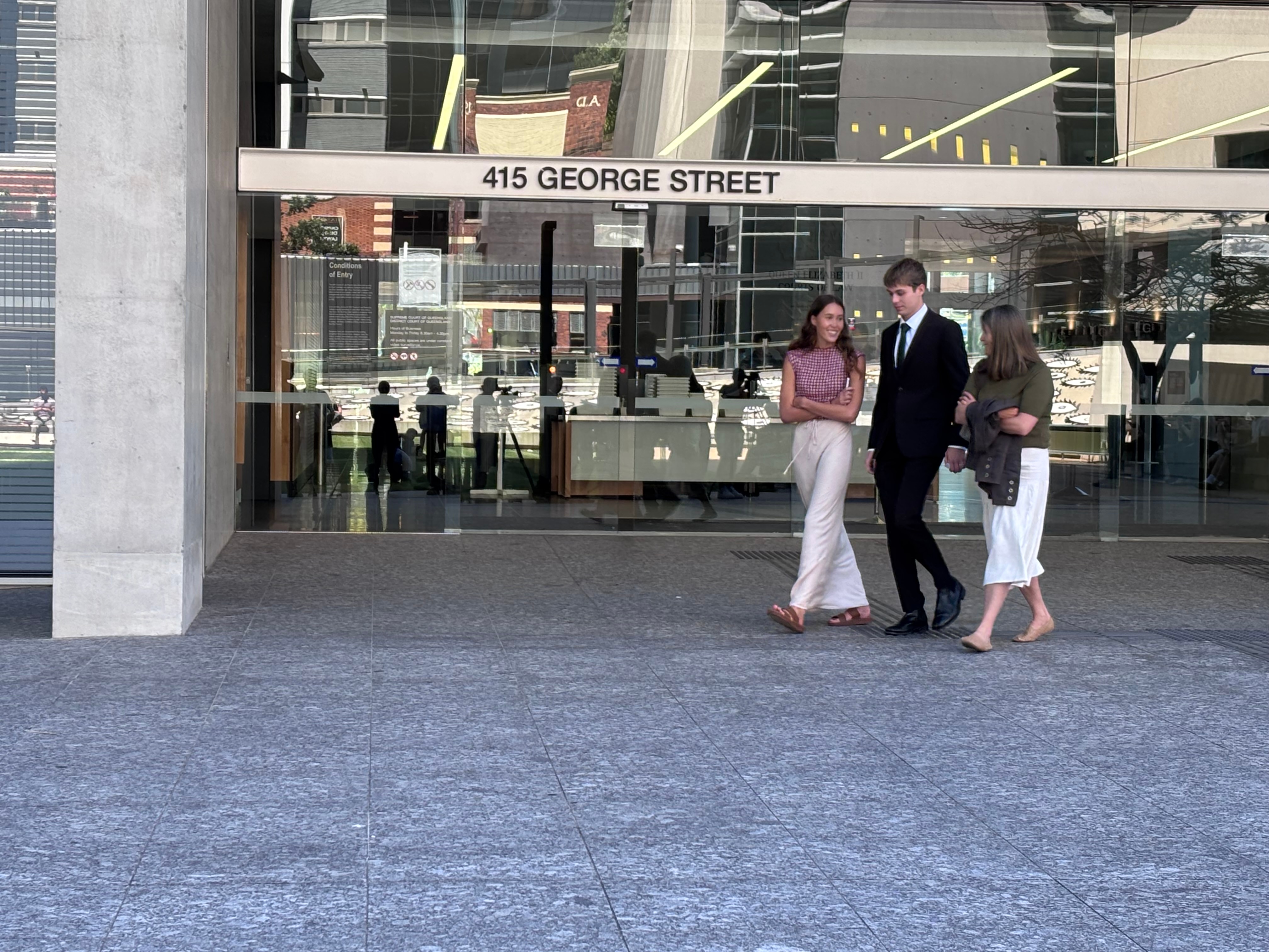 two women either side of a man walking out of brisbane's court building