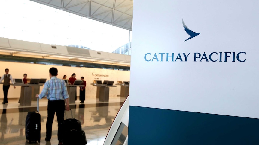 A passenger with suitcases walk up to the counter of Cathay Pacific.