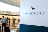 A passenger with suitcases walk up to the counter of Cathay Pacific.