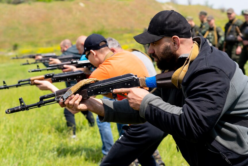 A row of men brandishing rifles in a field 
