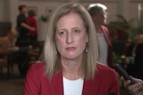 Katy Gallagher speaks to reporters while wearing a red blazer