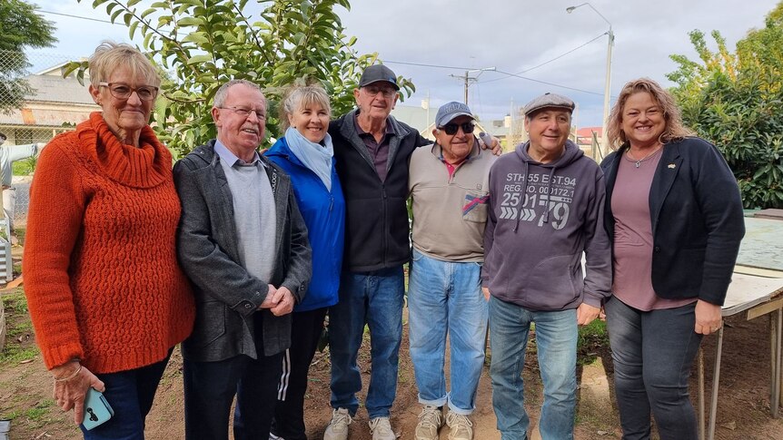 Politicians and members of a community garden stand beside each other outside.