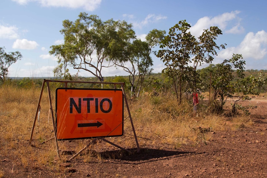 a road sign reading "NTIO" on the side of a dirt road.
