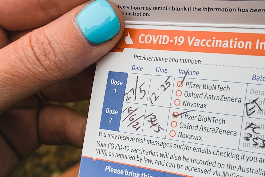 a close up image of a completed vaccination card in hand