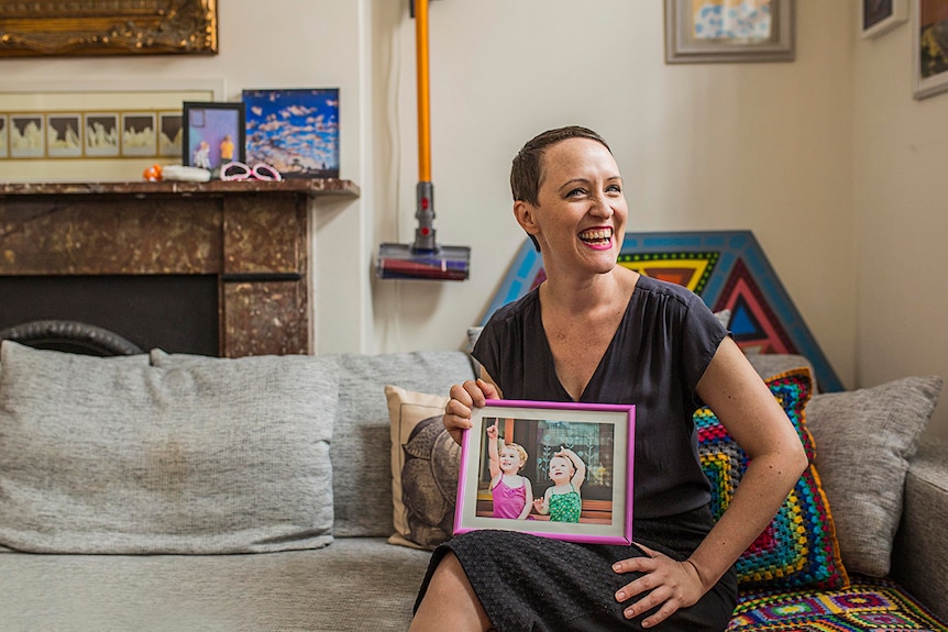 Christy Newman holding a holding framed photo of her children.