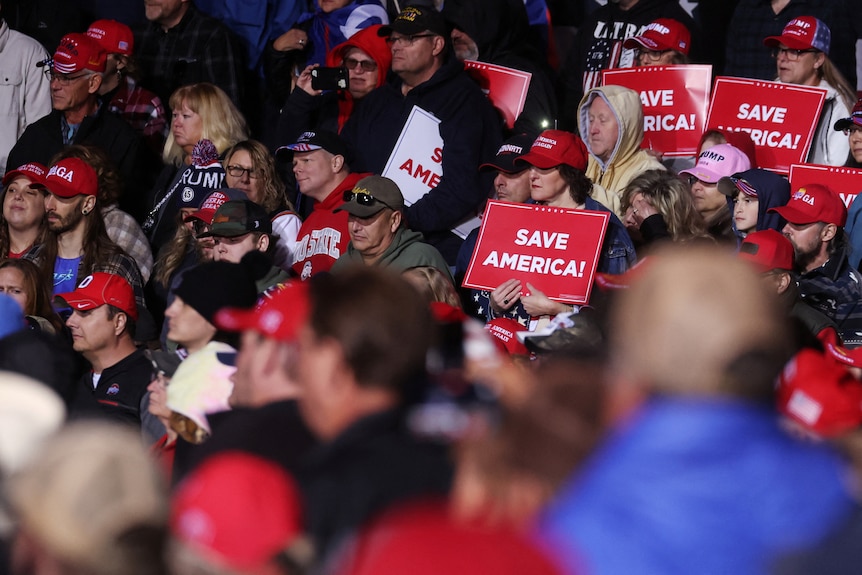 Толпа держит таблички с надписью "Спасите Америку!"