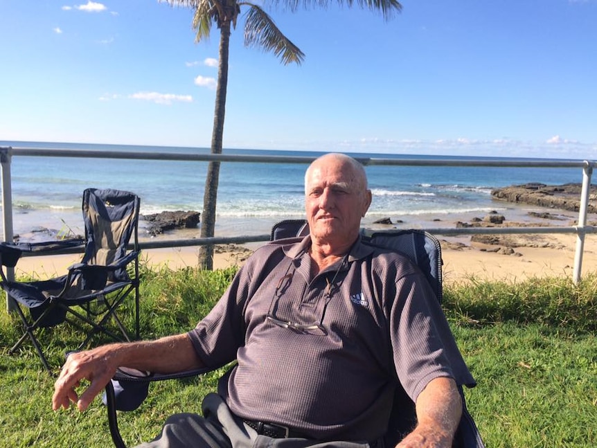 Man sits in camping chair with ocean in the background.