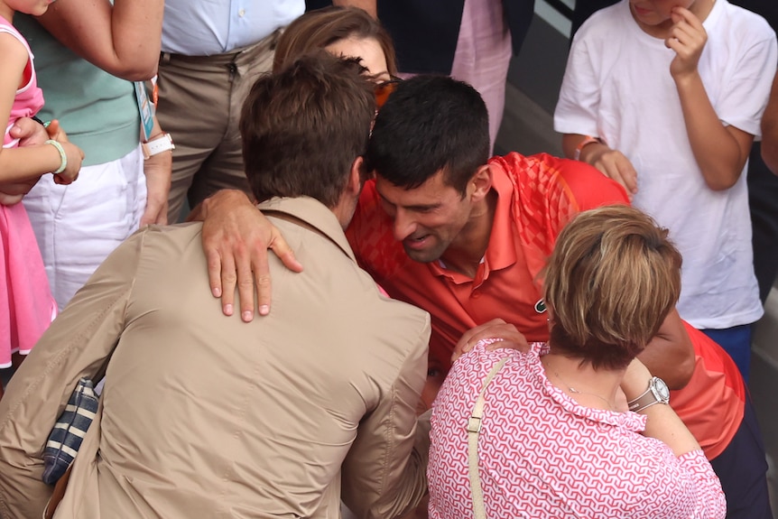 Novak Djokovic leans in to hug Tom Brady in a crowded grandstand after winning the French Open.