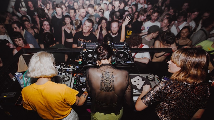 Three women DJ for a big crowd.