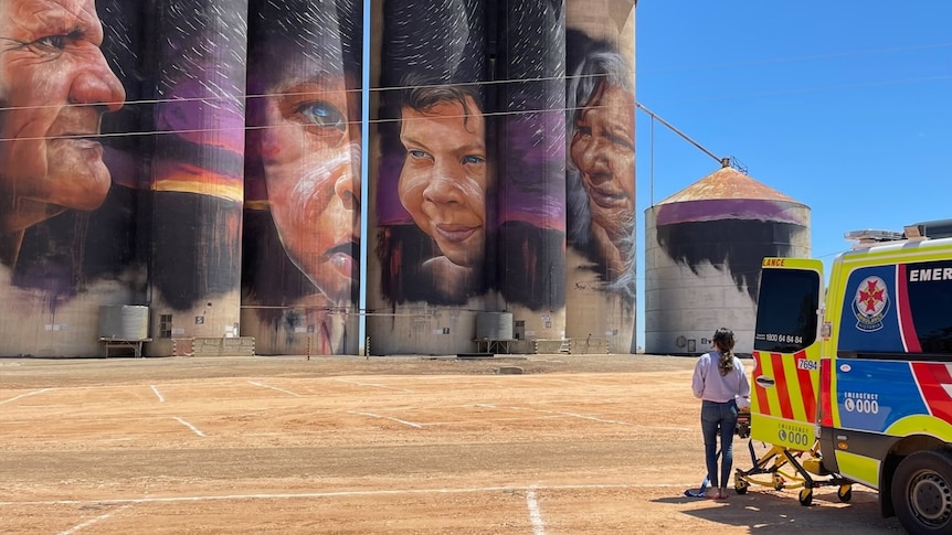 An ambulance sits on the right, with the silo artworks loom in the background 