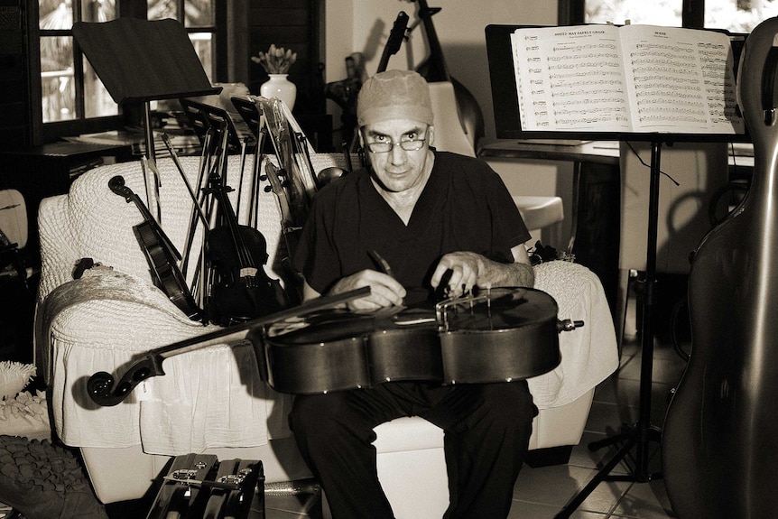 A man sits on a sofa surrounded by musical instruments.