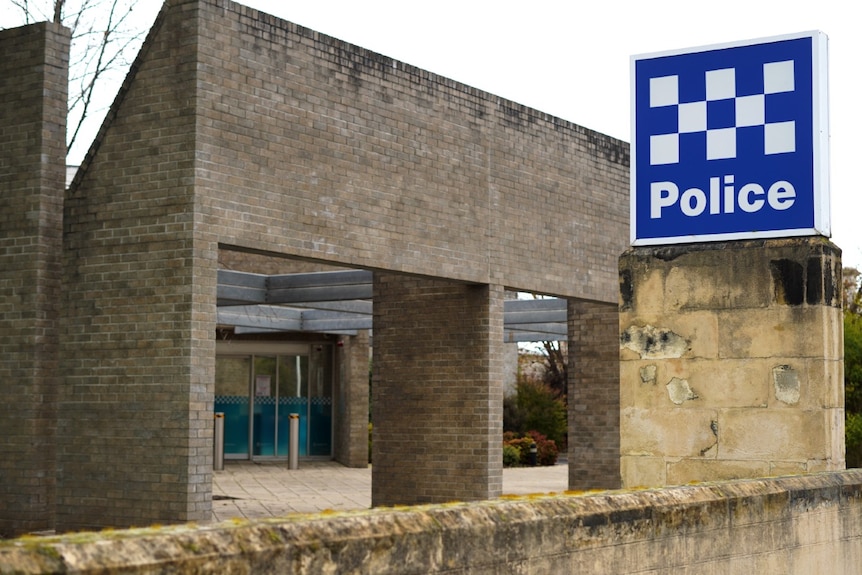 A large blue sign which says police in front of a large stone walkway. 