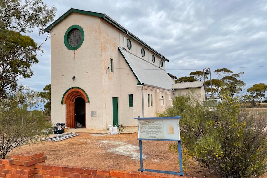 A tall thin barn like church building with circular window and door open 