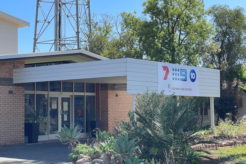 A modest-looking television bureau featuring a sign bearing the logos of several television networks.