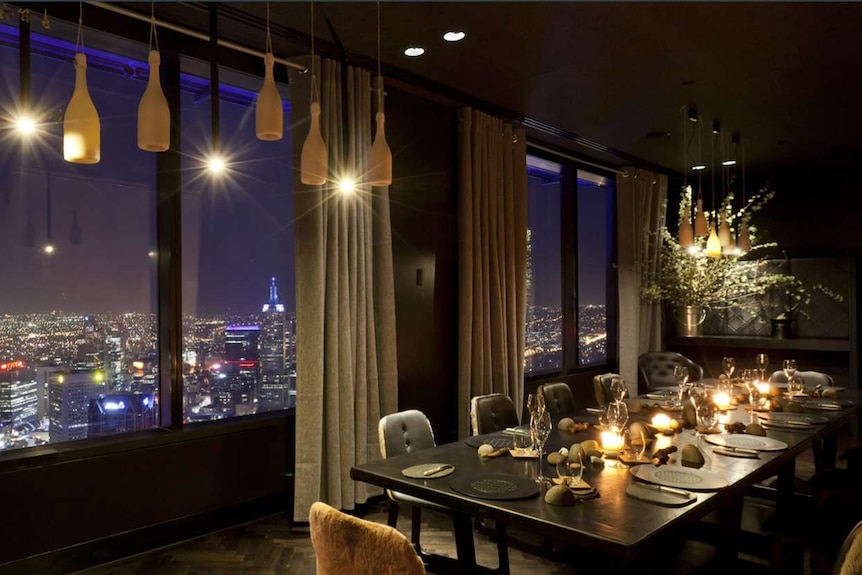 A dining table with views of Melbourne's skyline at night.