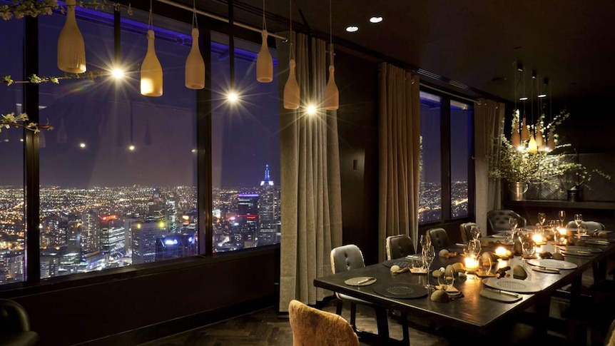 A dining table with views of Melbourne's skyline at night.