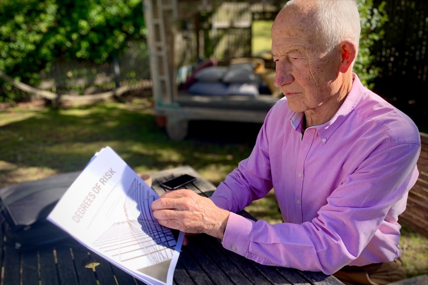 Man reads report at an outdoor table