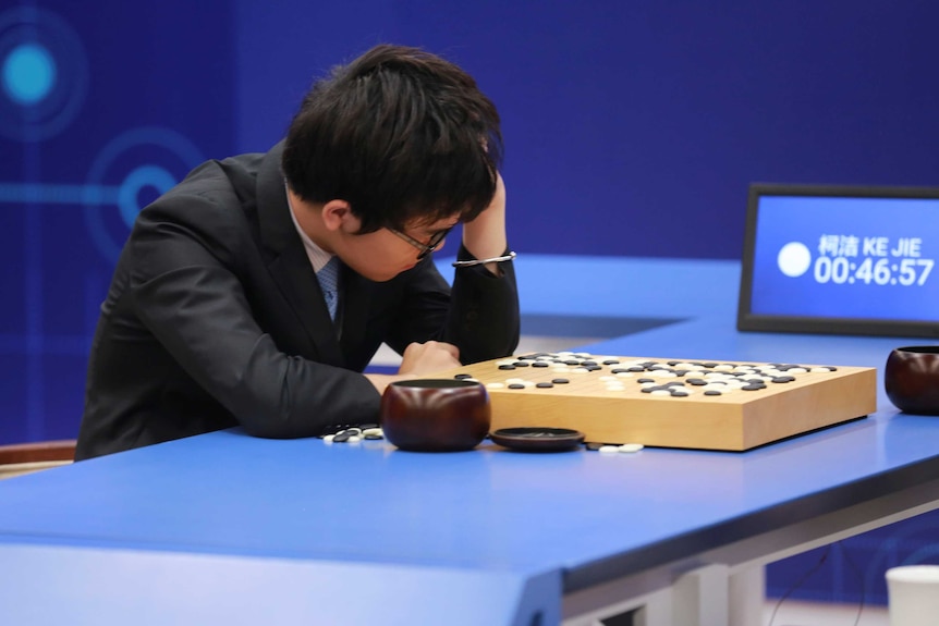 Ke Jie has his head in his hand as he looks at the Go board.