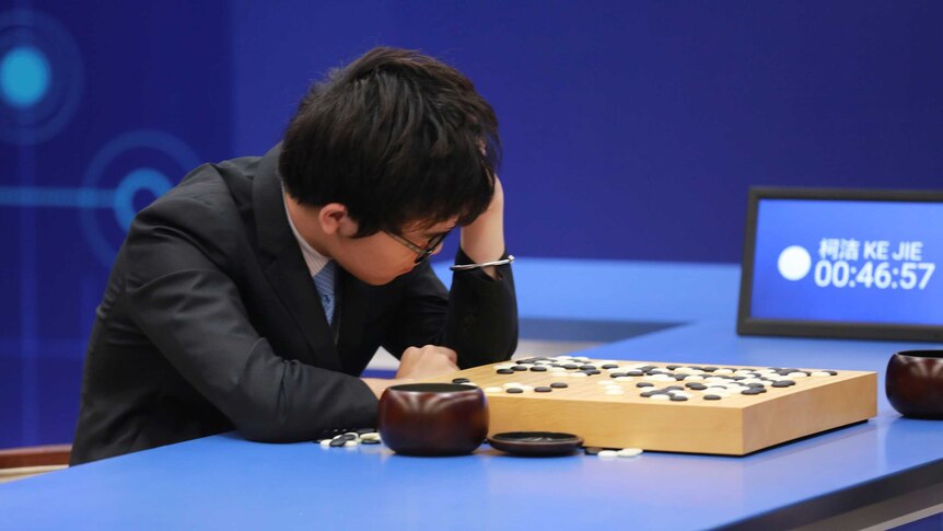 Ke Jie has his head in his hand as he looks at the Go board.